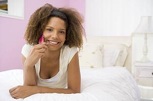 Teenage Girl Lying On Bed Using Cellphone
