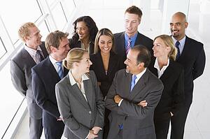 Group of co-workers standing in office space smiling (high key)