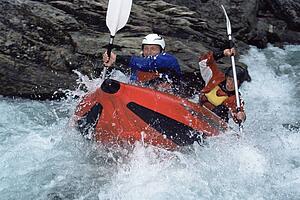 Two kayakers rowing in rapids