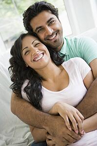 Couple in living room embracing and smiling (high key)