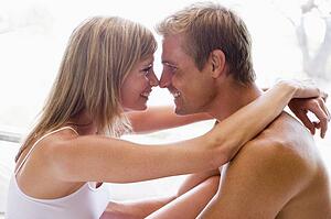 Couple in bedroom embracing and smiling