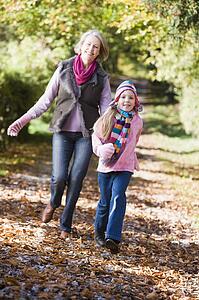 Grandmother and granddaughter running outdoors in park and smiling