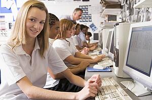Students working on computer workstations with teacher