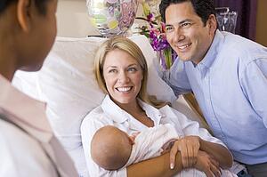 New parents with baby talking to doctor and smiling
