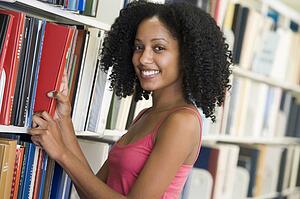 Woman in library pulling book off a shelf (depth of field)