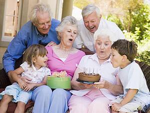 Grandparents and grandchildren on patio with cake and gift smiling