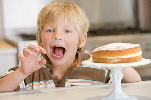 Young boy in kitchen with cake on counter