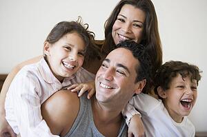 Family together on bed in bedroom smiling (selective focus)