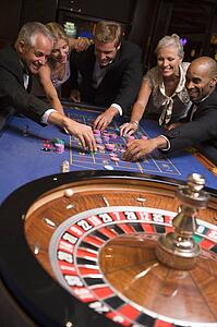Group of people in casino playing roulette and smiling (selective focus)