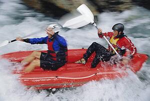 Two kayakers rowing in rapids and smiling (selective focus)
