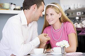 Young couple sitting at a table and having tea together