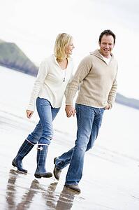 Couple walking on beach holding hands smiling
