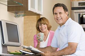 Couple in kitchen with coffee and newspaper smiling