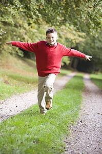 Young boy running on path outdoors smiling (selective focus)