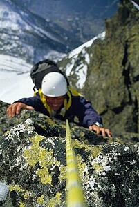 Mountain climber coming up snowy mountain smiling (selective focus)
