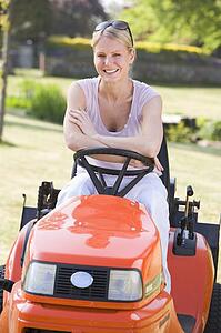 Woman outdoors with lawnmower smiling