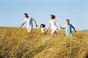 Family running outdoors holding hands smiling