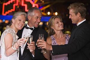 Two couples in casino toasting champagne smiling (selective focus)