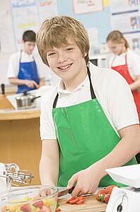 Male student slicing berries in cooking class