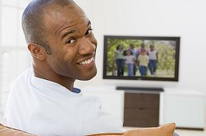 Man in living room watching television smiling