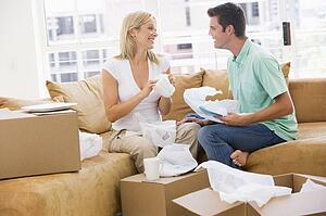 Couple unpacking boxes in new home smiling