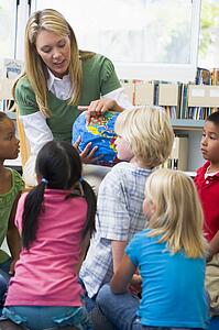Teacher in class showing students a globe (selective focus)