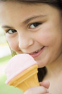 Young girl outdoors eating ice cream and smiling (selective focus)