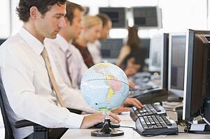 Five businesspeople in office space with a desk globe in foreground