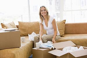 Woman unpacking boxes in new home smiling