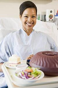 Woman Sitting In Hospital Bed With A Tray Of Food