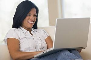 Woman in living room using laptop smiling