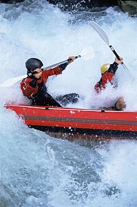 Two kayakers rowing in rapids