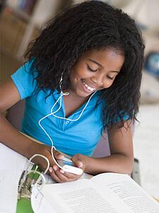 Young Girl Distracted From Her Homework, Playing With An MP3 Player