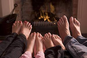 Family of feet warming at a fireplace