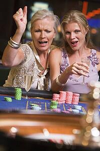 Two women in casino playing roulette and smiling (selective focus)