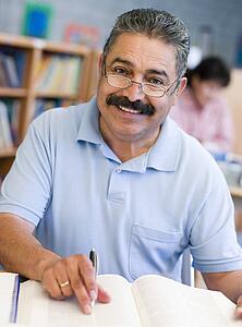 Man sitting in library with a book and notepad (selective focus)