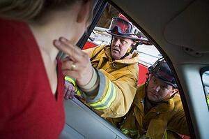Fireman taking woman's pulse while another fireman watches (selective focus)