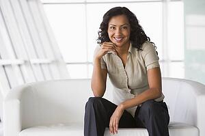 Businesswoman sitting indoors smiling (high key/selective focus)