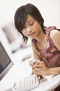 Woman in computer room listening to MP3 player