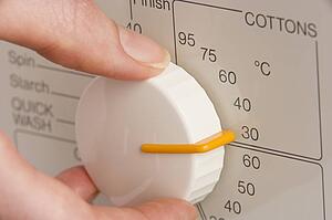 Person Adjusting Washing Machine Dial To Cold Wash