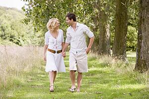 Couple walking on path holding hands smiling