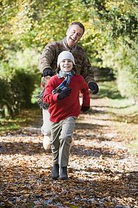 Grandfather and grandson running outdoors in park and smiling