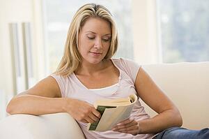 Woman in living room reading book