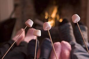 Feet warming at a fireplace with marshmallows on sticks