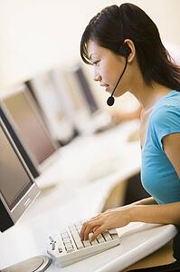 Woman wearing headset sitting in computer room typing