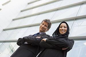 Two businesspeople standing outdoors by building smiling (selective focus)
