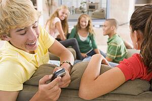 Teenagers Hanging Out In Front Of Television Using Mobile Phones 