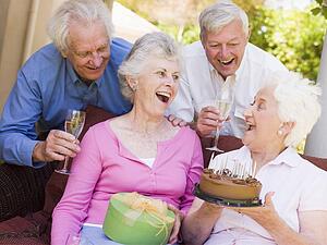 Two couples on patio with cake and gift smiling