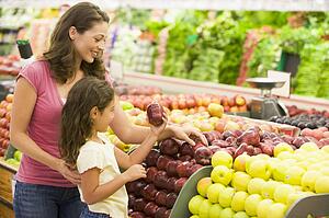 Woman and daughter shopping for apples at a grocery store