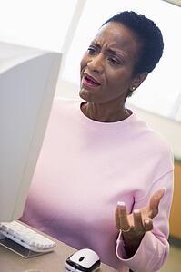Woman at computer looking at monitor frustrated (high key)